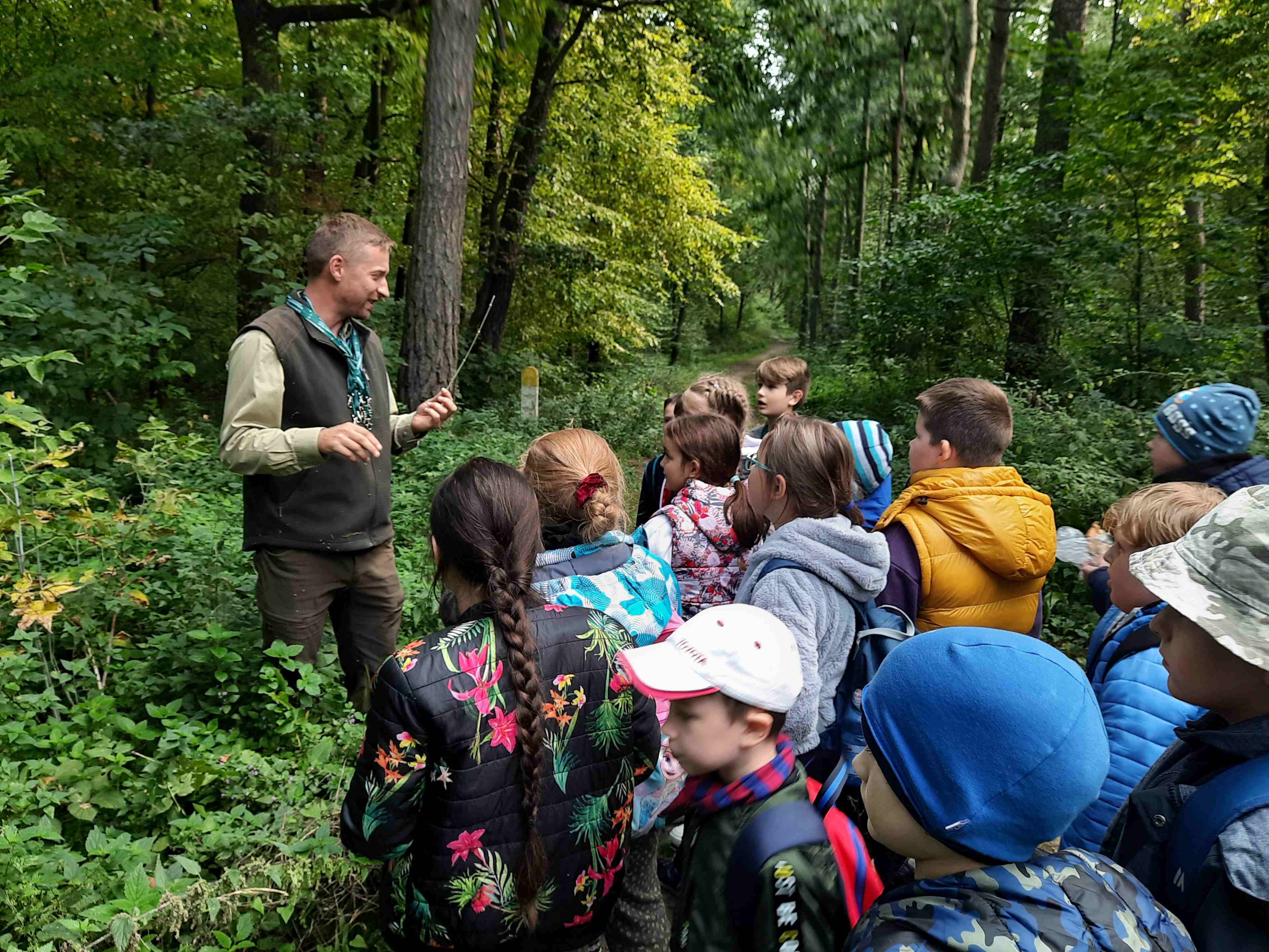 Dzieci rozmawiają z leśniczym w lesie
