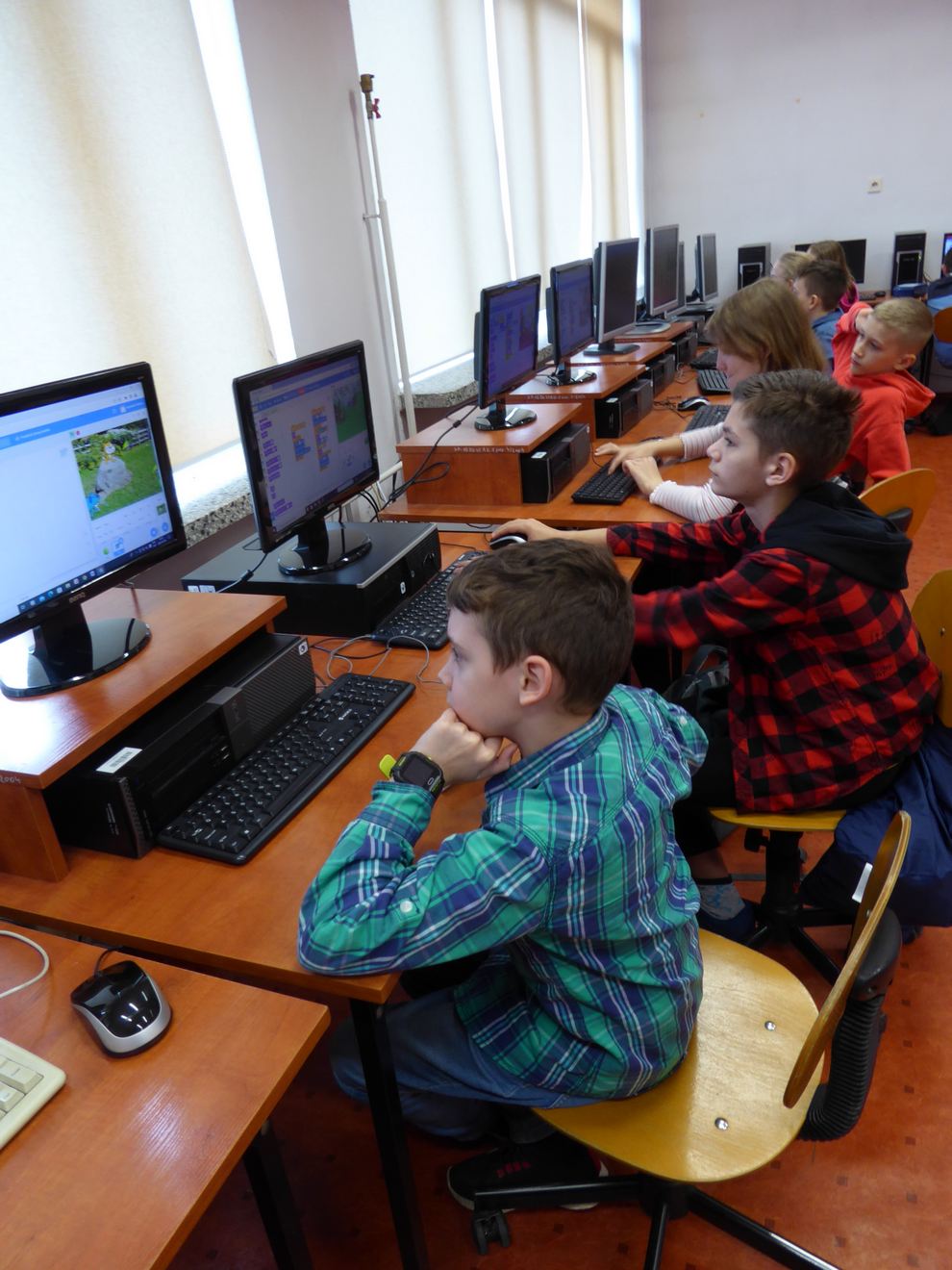 Dzieci siedzą przy komputerach i programują w Scratchu 