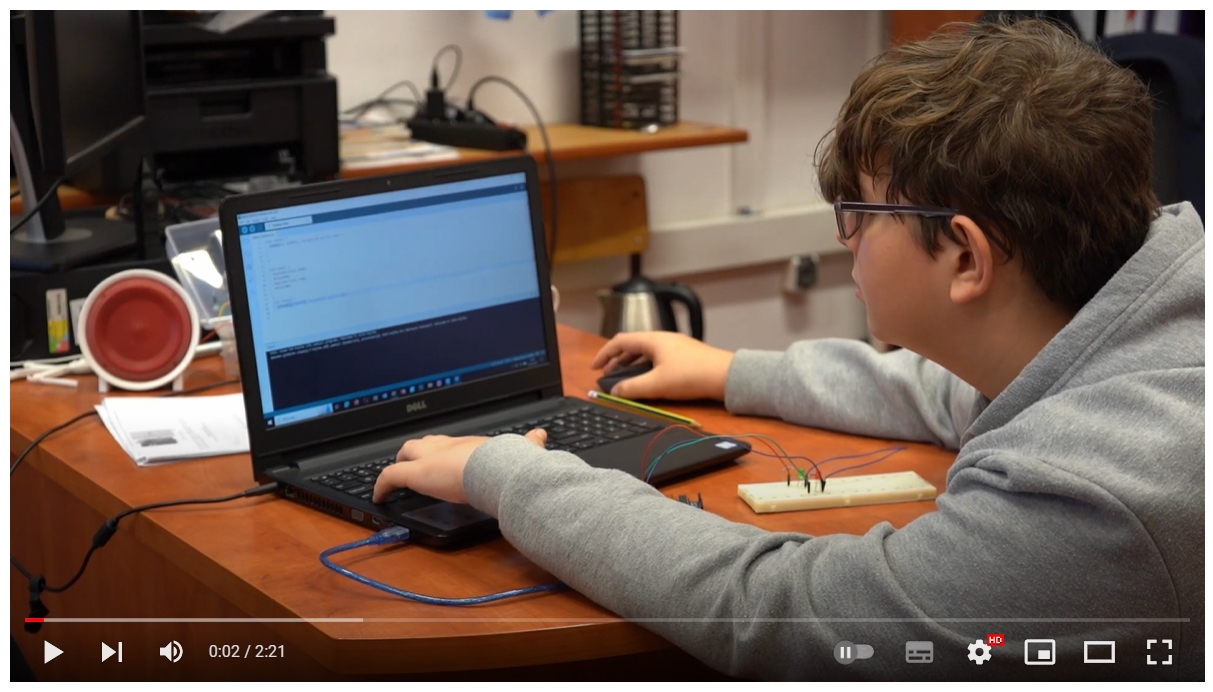 Uczeń siedzi przed laptopem i wpisuje kod programu