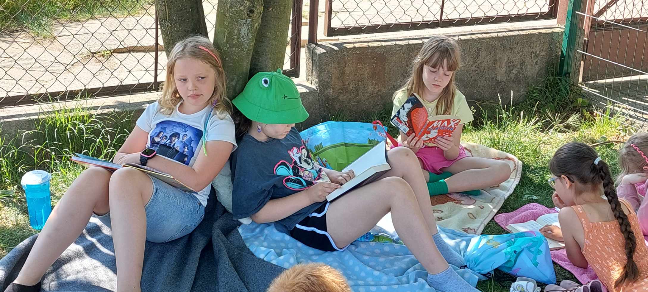 Dzieci czytają książki pod drzewem